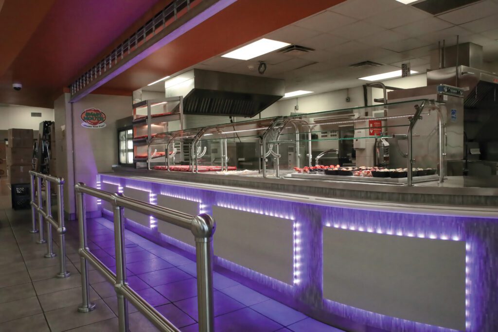 Custom serving line with glass food guards and illuminated front panels in a restaurant