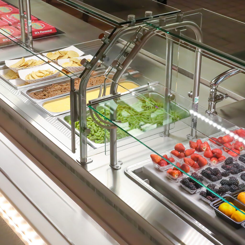Serving line with glass food guards, taco bar toppings and fresh fruit displays