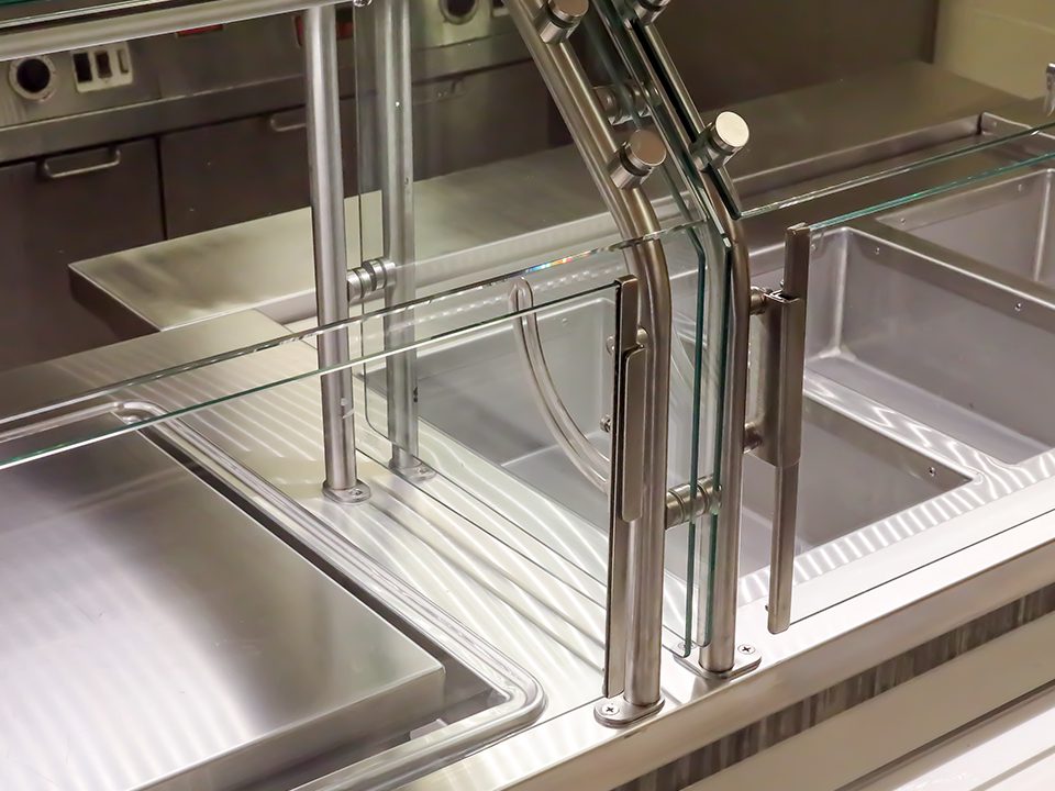 Close-up of a drop-in serving unit with glass food guard and stainless steel pans