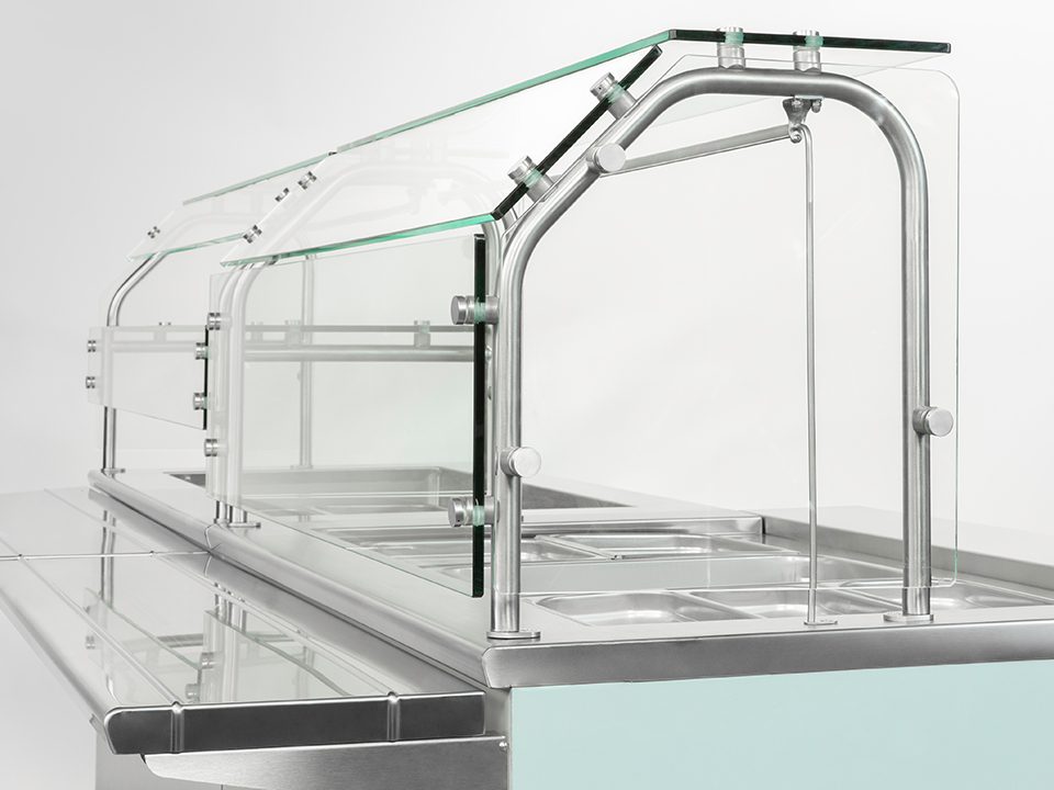 Glass food guard with stainless steel supports on a serving line