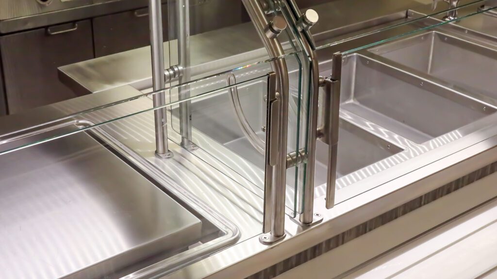 Close-up of a drop-in serving unit with glass food guard and stainless steel pans