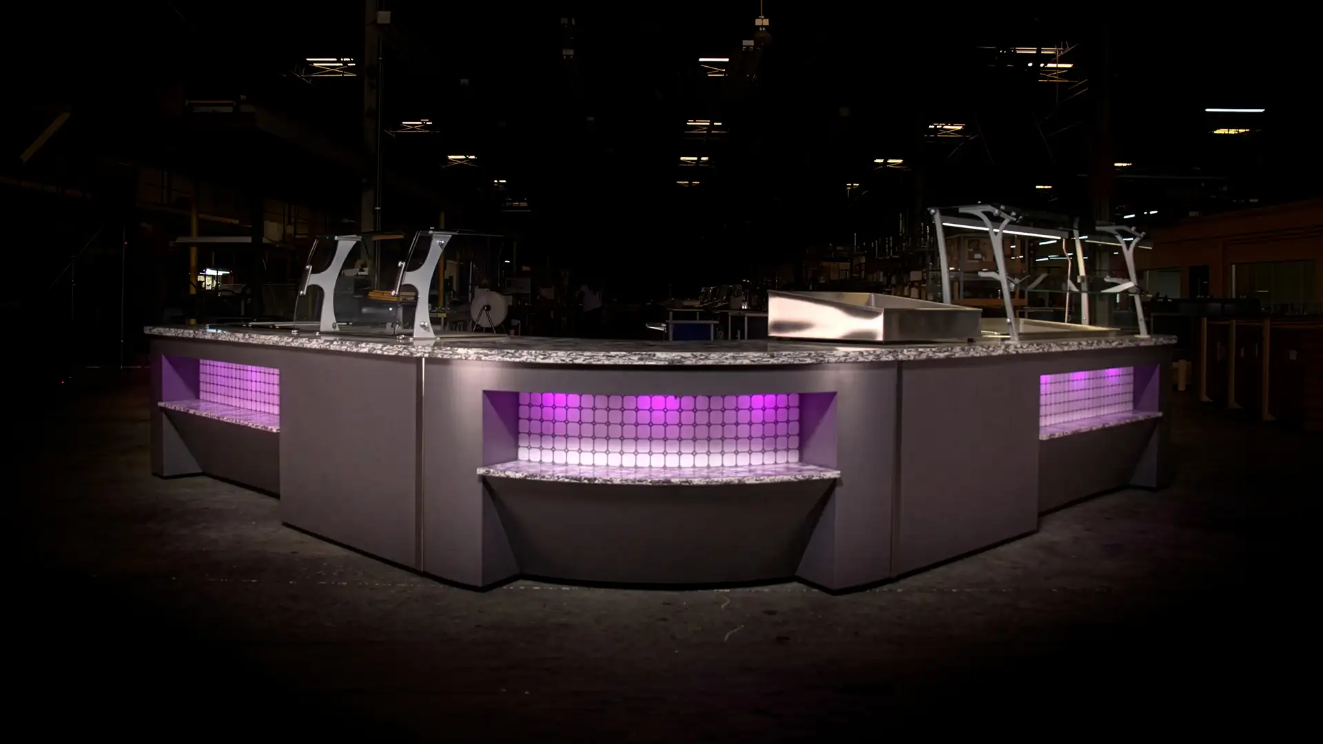 Custom serving line with glass food guards, stone-look countertop and purple accent lighting.