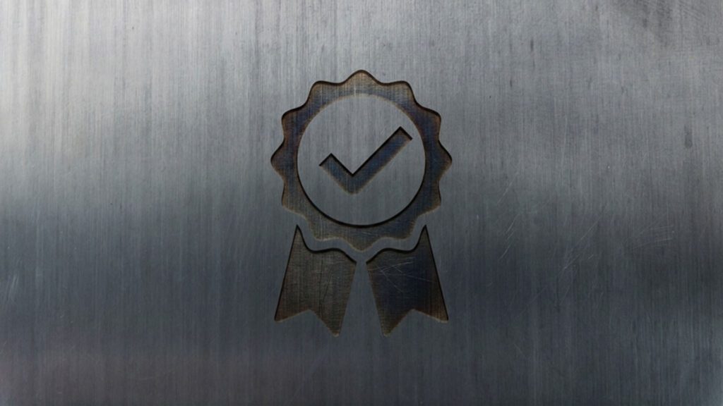 Warranty logo featured image of a ribbon with a check mark on a gray steel background.